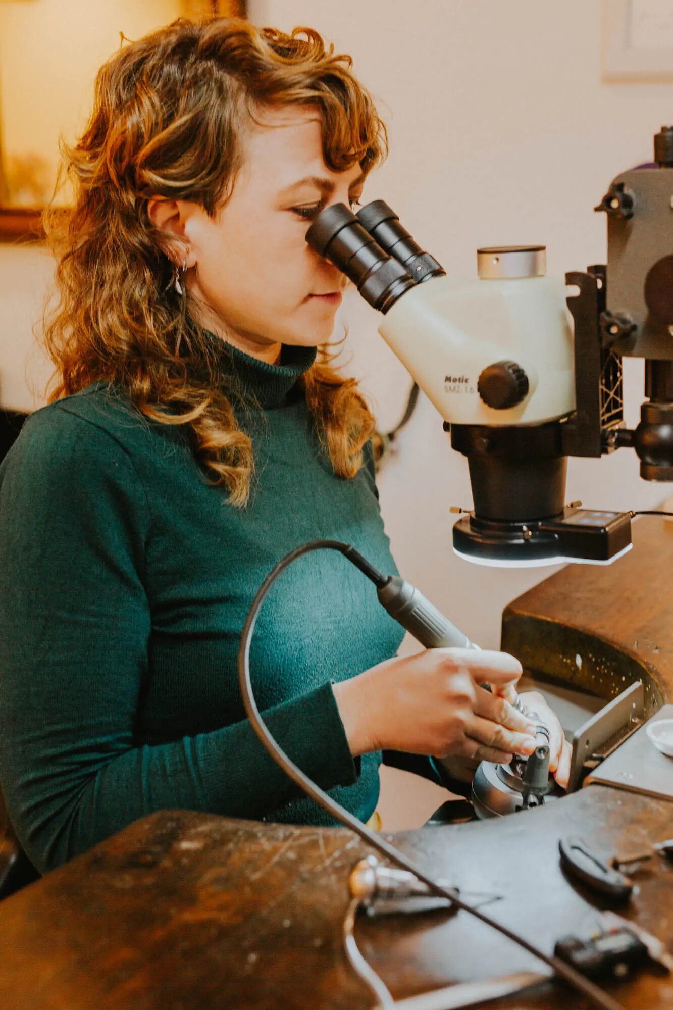 Maren Baum beim Edelsteinfassen am Mikroskop in ihrem Atelier in Tübingen